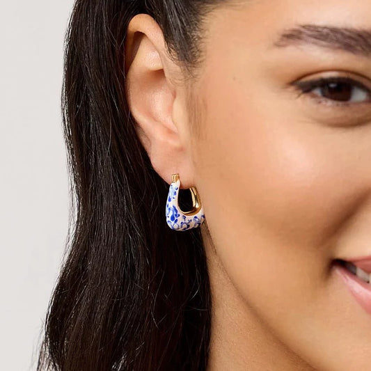 Gold hoop earring with blue marbled teardrop detail, worn