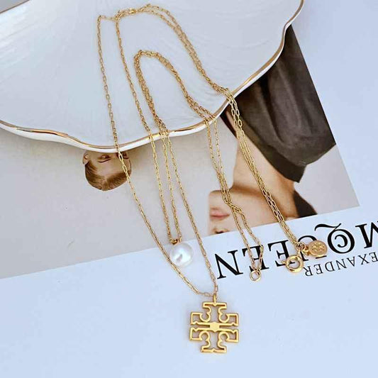 Gold multi-chain necklace with pearl charm and geometric logo pendant, link chain.