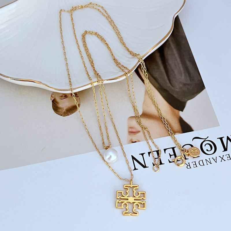 Gold layered necklace with pearl drop and geometric logo pendant, dangling pearl bead.