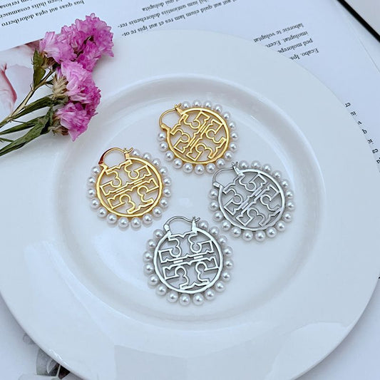 Round logo earrings with pearl border, showing gold and silver-tone versions