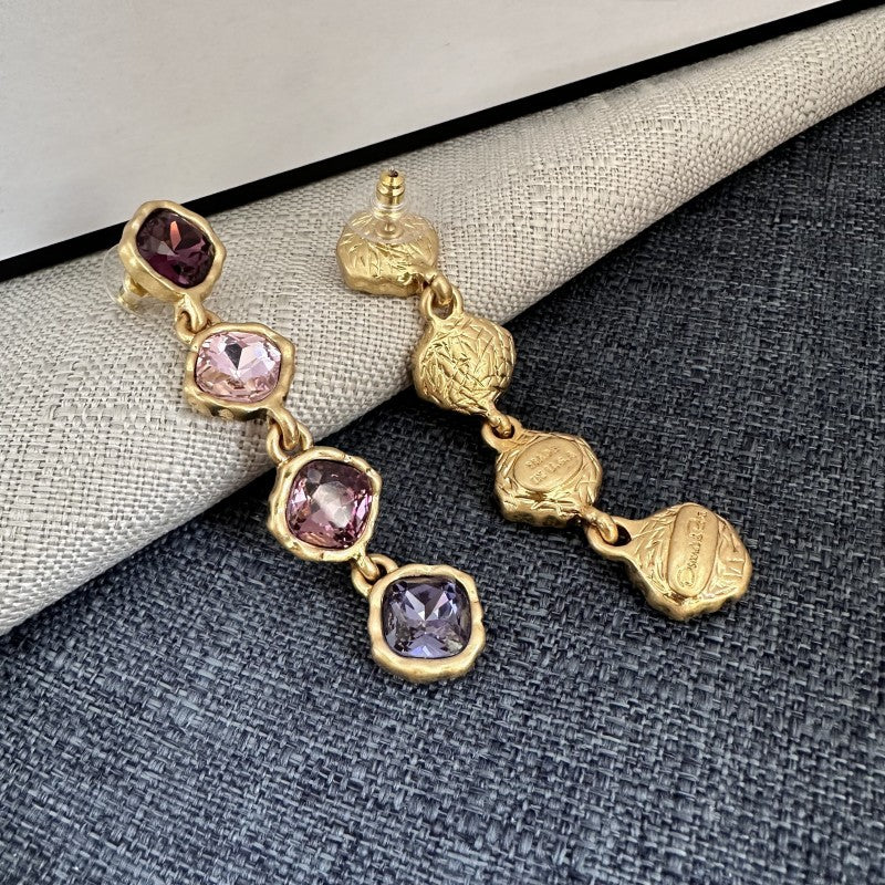 Gold-tone purple crystal drop earrings with square settings and stud backing, dangle style.