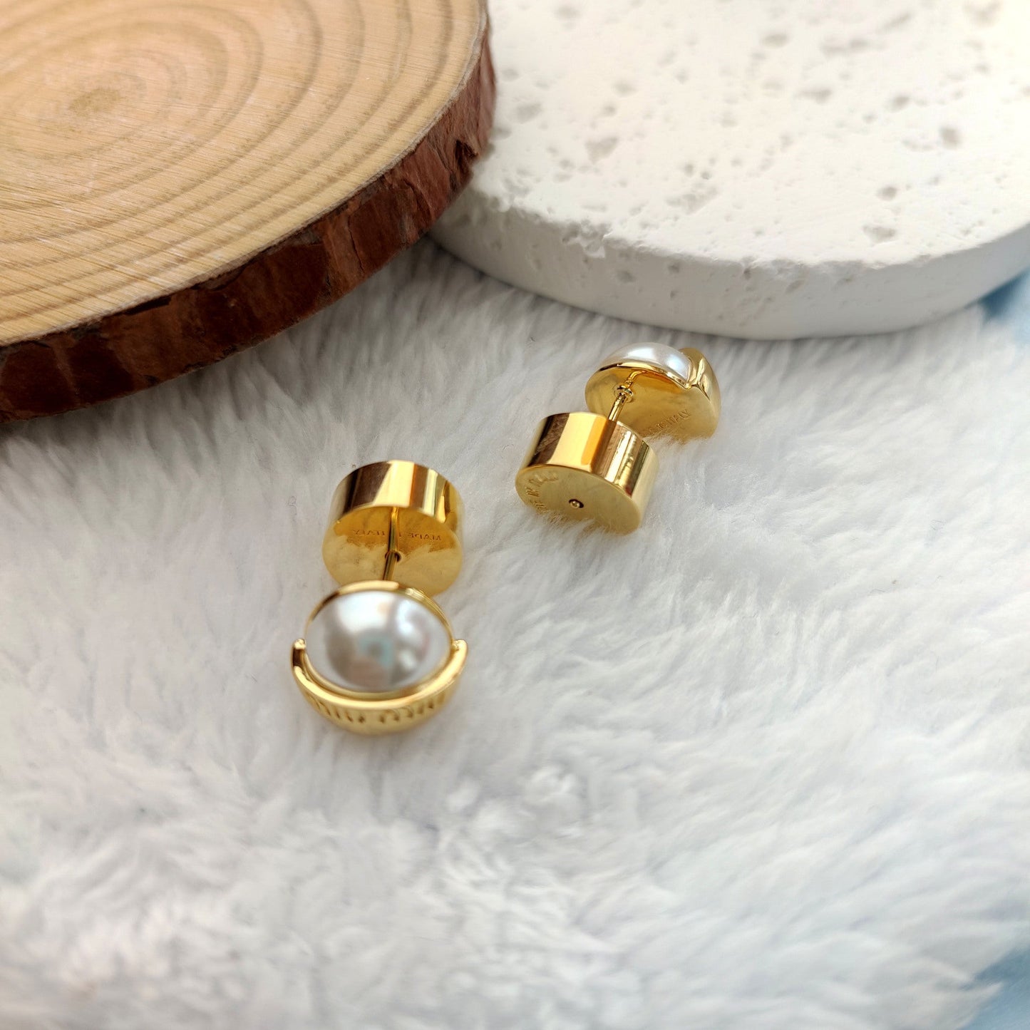 Gold half-circle pearl stud earrings with back posts visible