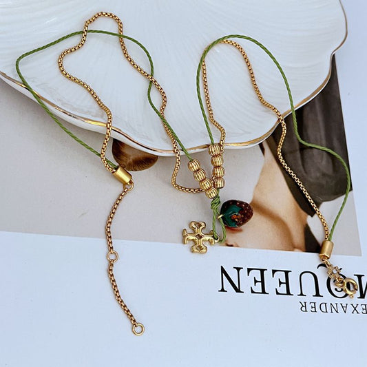 Gold-tone double necklace with red enamel berry charm, green thread, and clasp