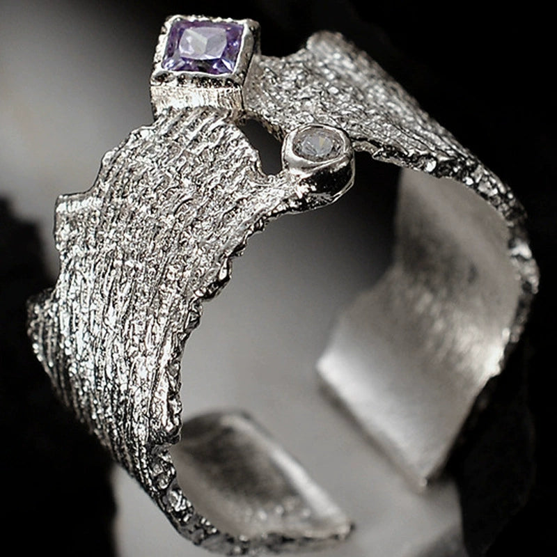 Textured silver open band ring close-up with square purple gem and round clear stone