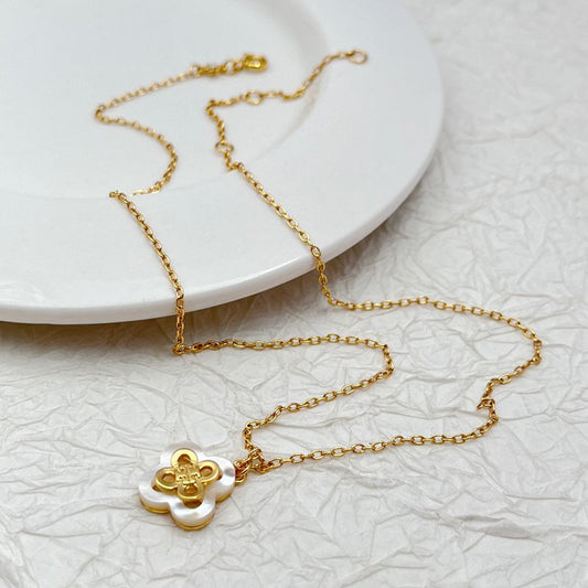 Gold-tone necklace with white inlaid four-leaf clover pendant on fine chain