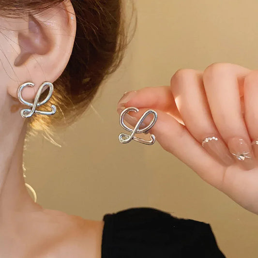 Geometric logo stud earrings in silver tone, looping ribbon design with cutout detail