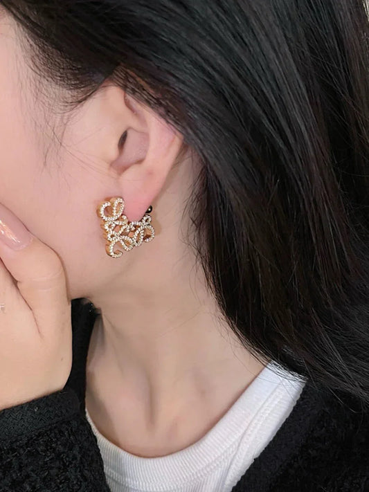 Gold-tone geometric hollow diamond stud earrings on ear
