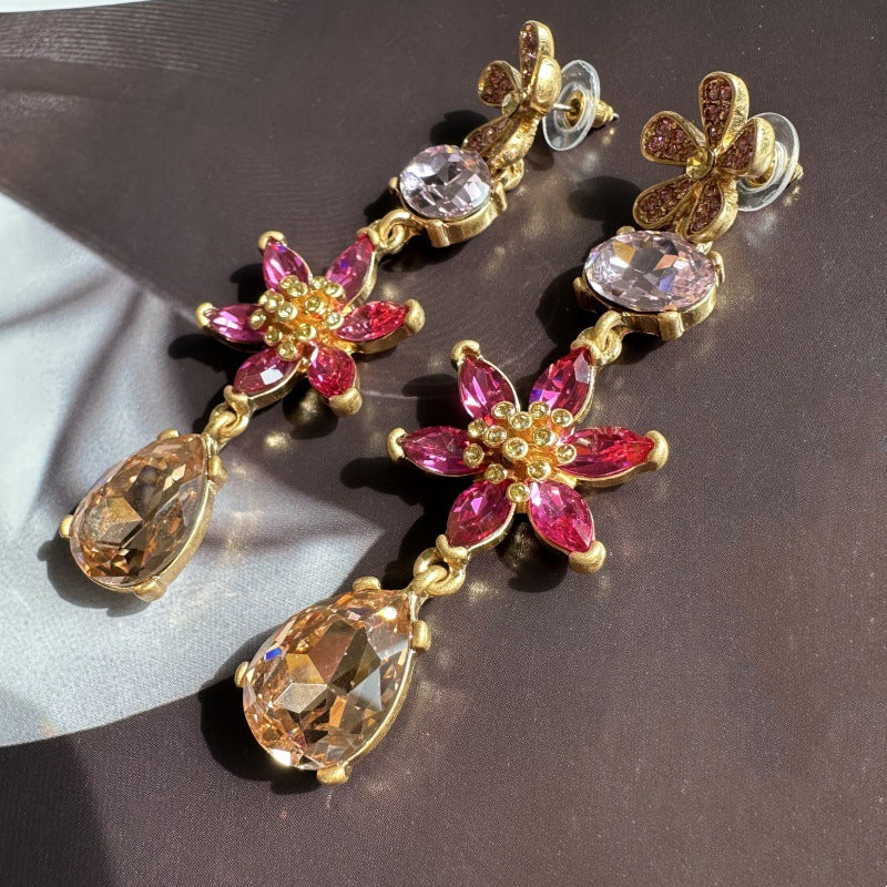 Floral crystal teardrop earrings with pink petals, clear stones, and gold-tone drops