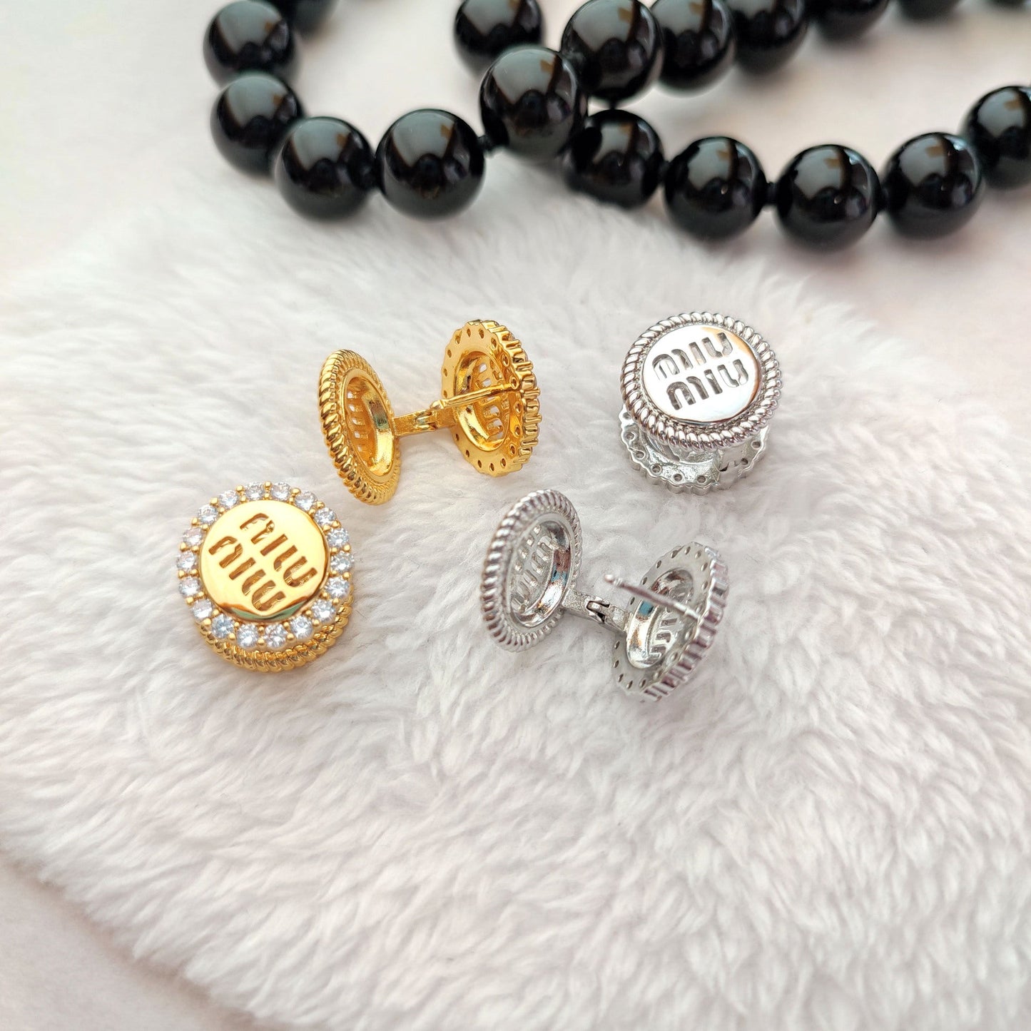 Round enamel stud earrings in gold and silver-tone, crystal halos with logo centers