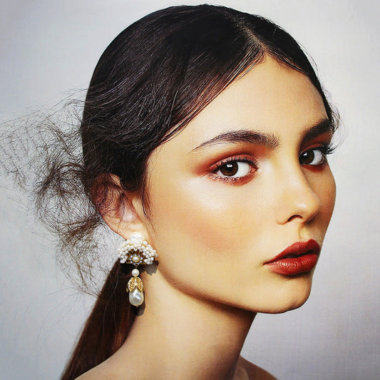Fan-shaped pearl drop earrings worn on ear, with gold crown details and teardrop pearl