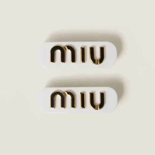 White hair clip set with gold “miu” lettering, rhinestone accents, 2 pieces