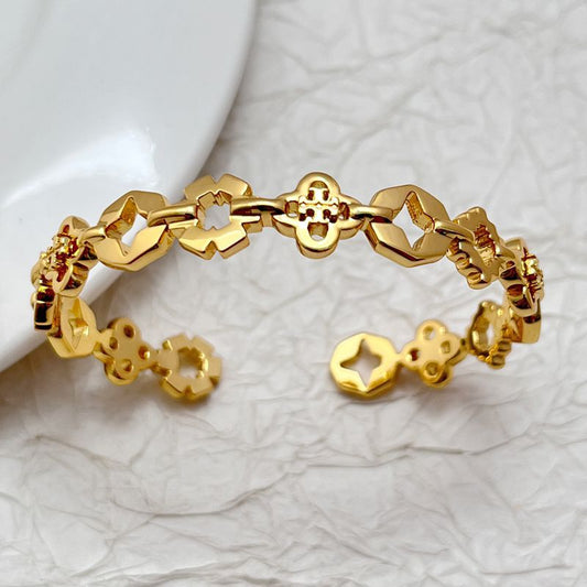 Gold-tone bangle viewed from above, featuring clover and star motifs in openwork