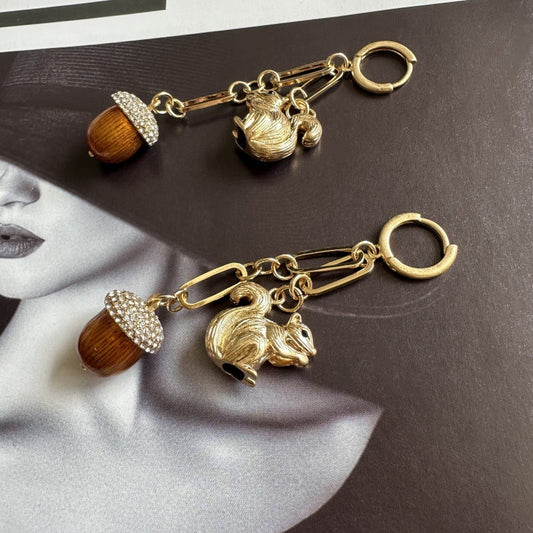 Gold-tone squirrel earrings with orange acorn bead, rhinestone cap, and hoop clasp