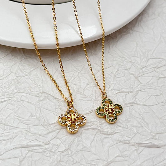 Gold tone clover necklace with four-leaf pendant, green accents, rhinestone detail
