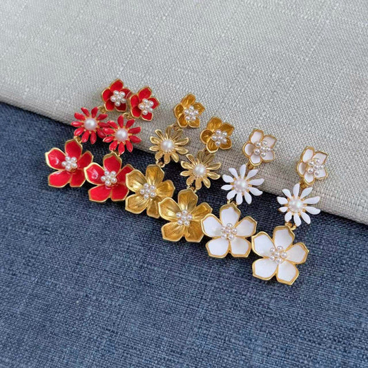 Gold drop earrings with red enamel flowers, pearl centers, and white accents