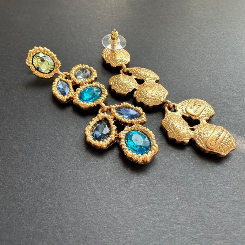 Blue crystal drop earrings with gold-tone back stud and dangling oval crystals in scalloped frames