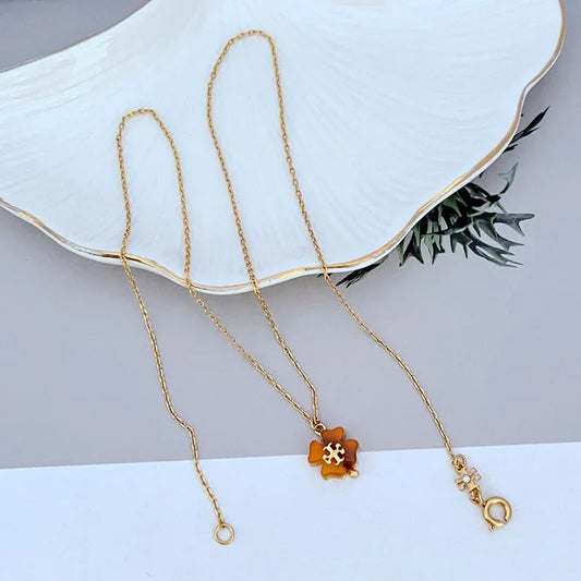 Tory Burch flower charm metal necklace with gold chain, orange pendant and cream stone charm