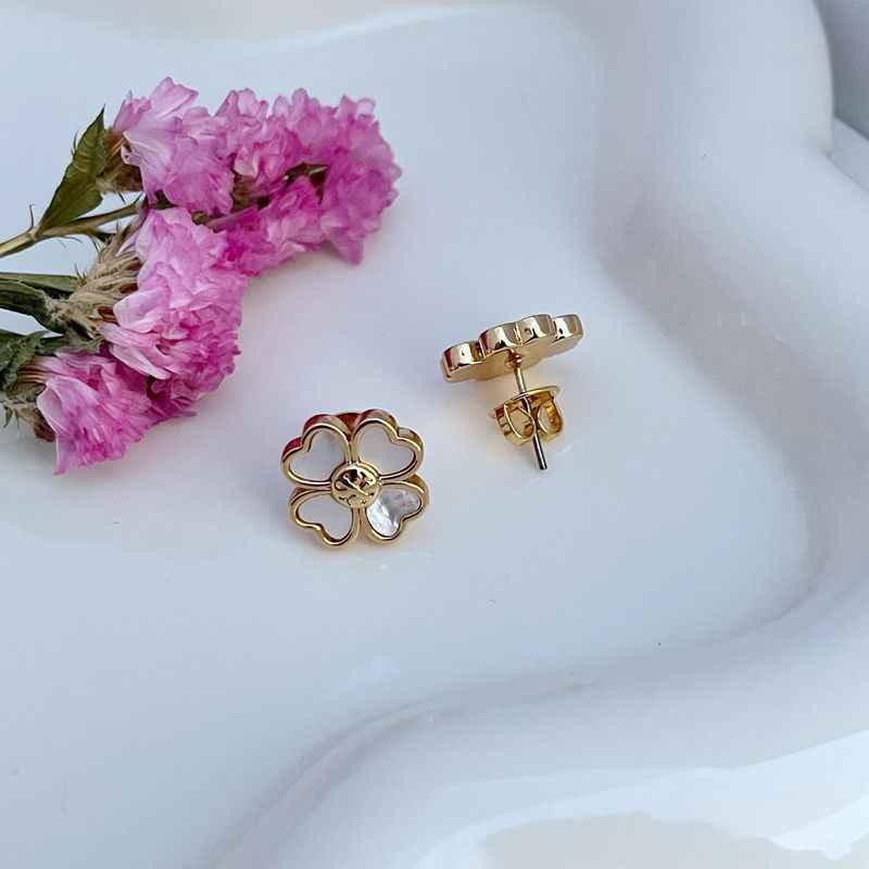 Gold four-leaf clover stud earrings with white enamel petals and post backing