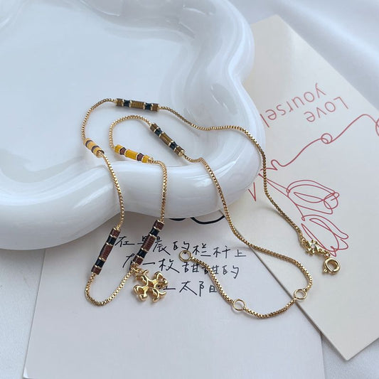Gold-tone beaded pendant necklace with yellow, black and white bead segments