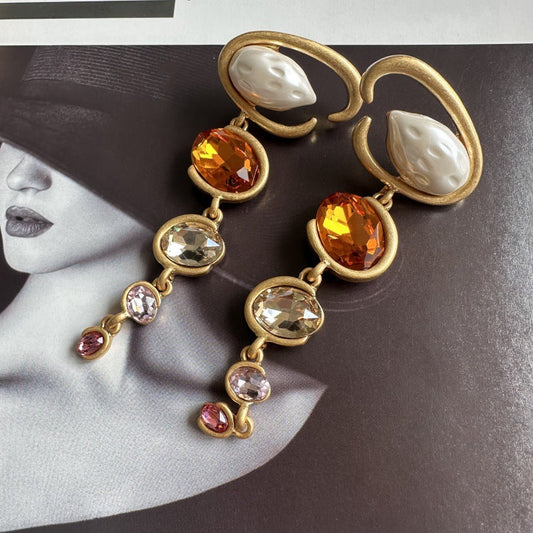 Oscar de la Renta long crystal drop earrings with warm orange, yellow, and clear stones, gold tone.