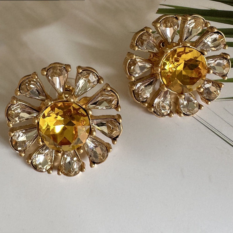 Gold-tone flower stud earrings with round yellow center and clear teardrop stones.