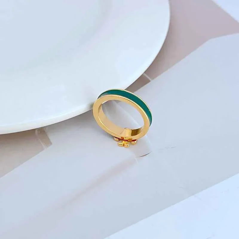 Enamel ring with gold-tone bezel, small raised emblem, and green enamel band