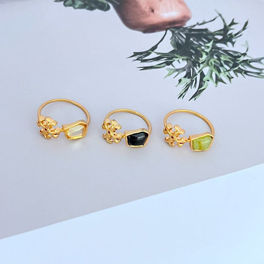 Three logo rings: transparent, black, and green acrylic stones in gold-tone