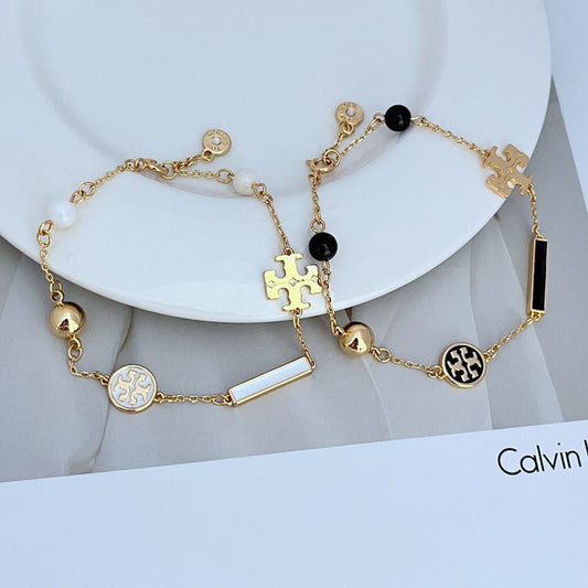 Gold-tone logo charm bracelet with black beads and enamel puzzle-piece and bar charms