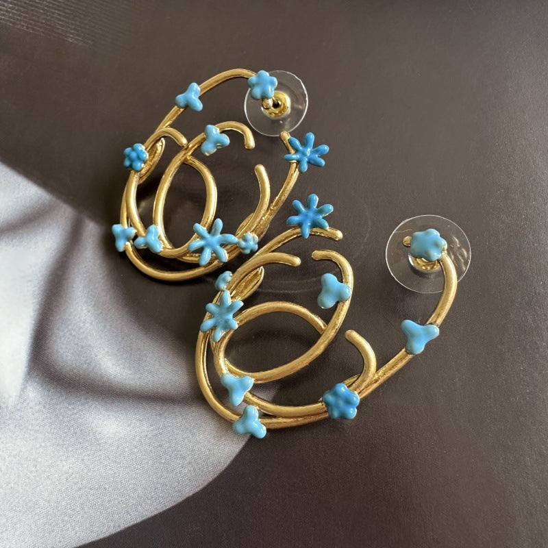 Gold-tone hoop earrings with blue enamel flower charms, overhead pair view
