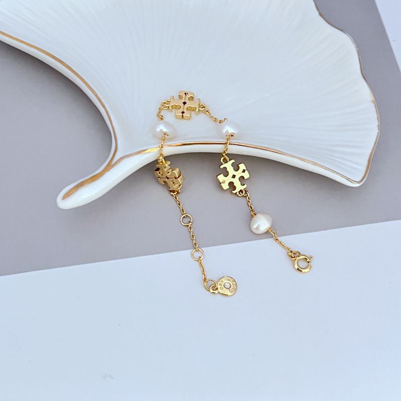 Gold-tone bracelet with quatrefoil charms, white pearl drops, and lobster clasp