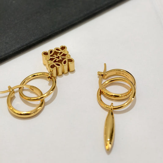 Gold asymmetrical hoop earrings with ornate pendant charm and dangling drop
