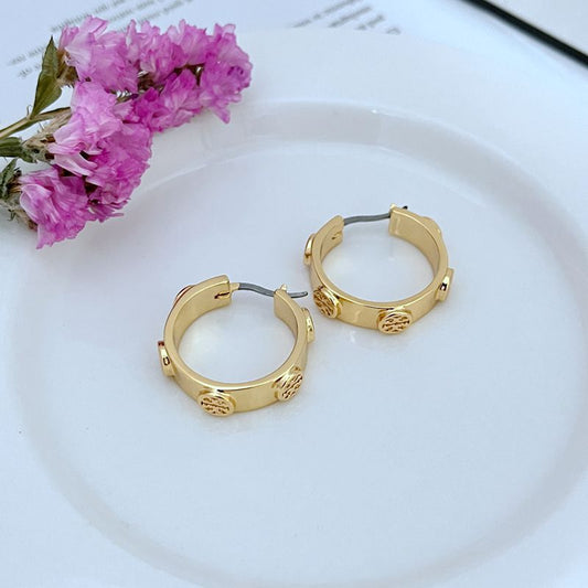 Pair of gold hoop earrings with embossed logo details and hinged clasps