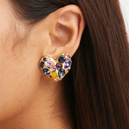 Heart-shaped crystal stud earrings on model ear, gold tone with blue, pink, purple stones