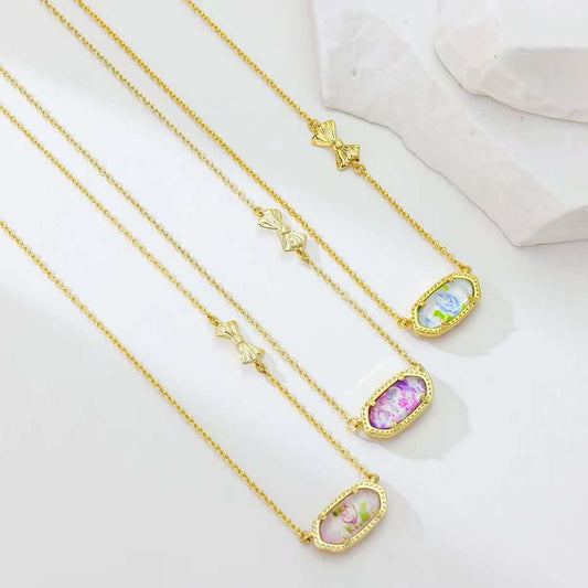 Gold butterfly pendant necklace with multiple oval charms in blue, pink, and purple