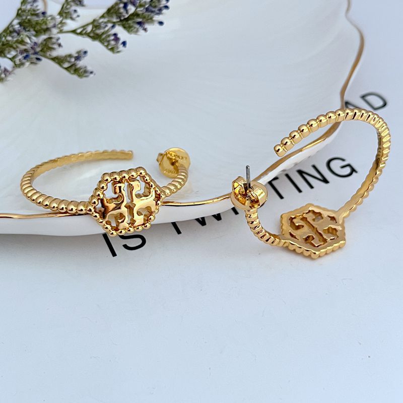 Gold C-shaped hollow metal earrings with square cutout logo centerpiece and stud back