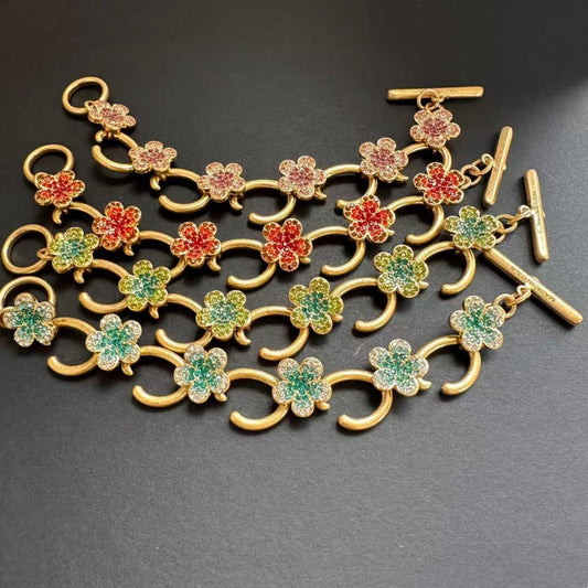 Gold-tone bracelet featuring repeating flower charms with multicolor enamel and pave stones