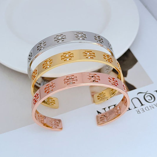Stacked open bangles: silver, gold, and rose gold with repeating logo cutouts