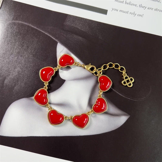Heart bracelet with red enamel heart charms and gold-tone chain, hinged clasp and logo charm