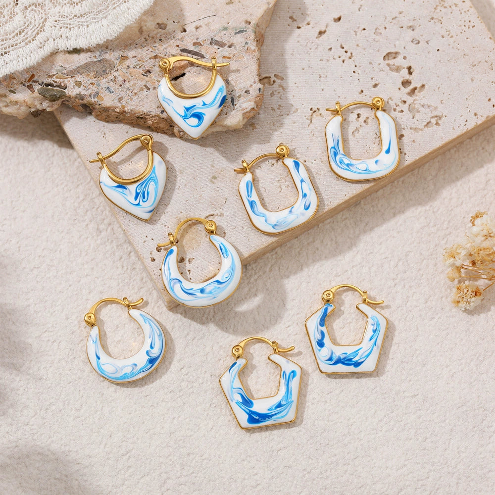 Blue marble gold-tone earrings assortment on stone, featuring hoops and drops