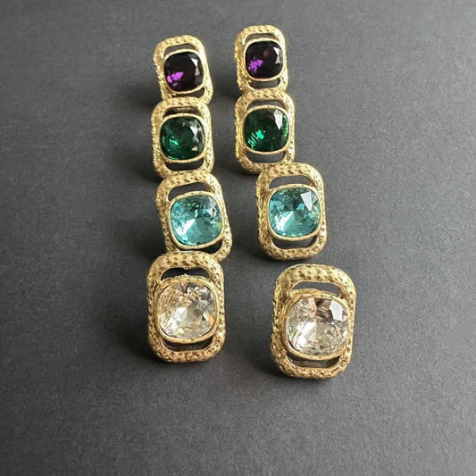 Square crystal stud earrings with purple, green, teal, and clear stones in gold-tone settings.