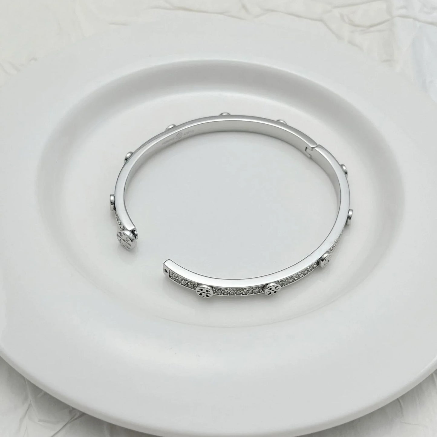 Silver-tone open cuff bracelet with clear rhinestone band and small end medallions