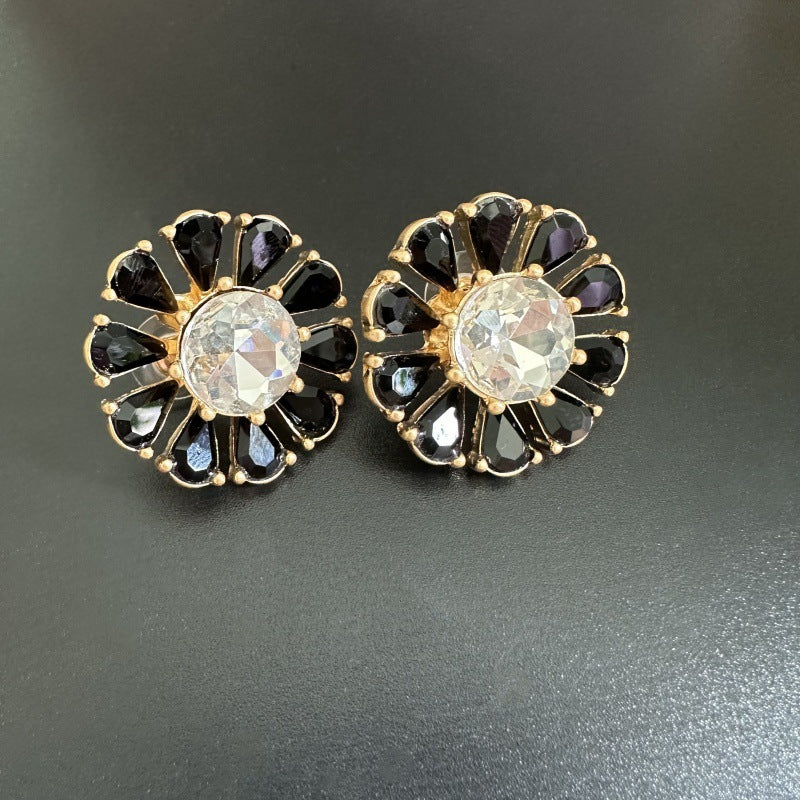 Sunburst flower stud earrings with black teardrop stones and clear round center.