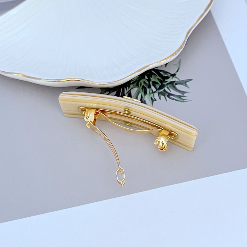 Milky white acrylic hair clip back view with gold-tone spring clasp
