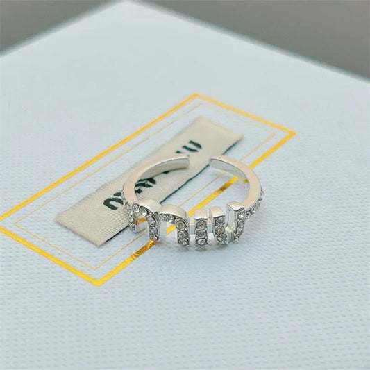 Offener Ring mit goldfarbener Fassung und klaren Steinreihen, seitlich