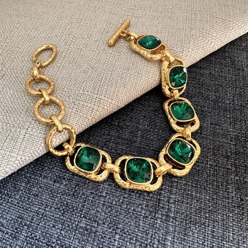 Gold-tone crystal toggle bracelet with dark green square stones, oval bezel link chain