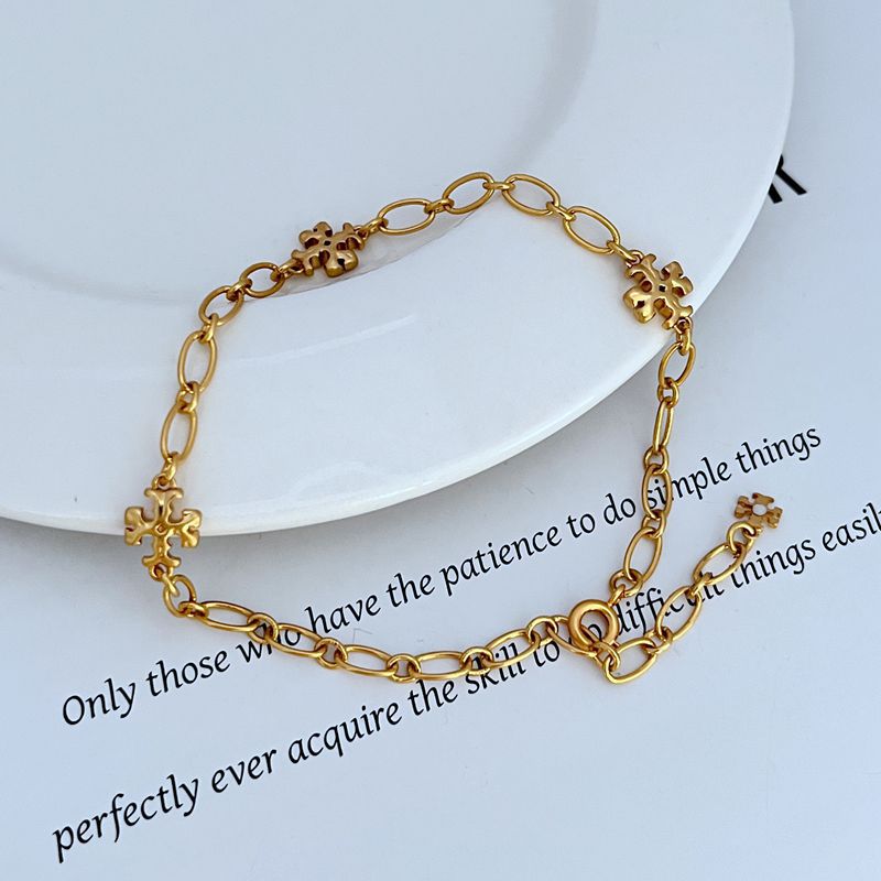 Gold-tone chain bracelet with clover logo charms and adjustable ring links