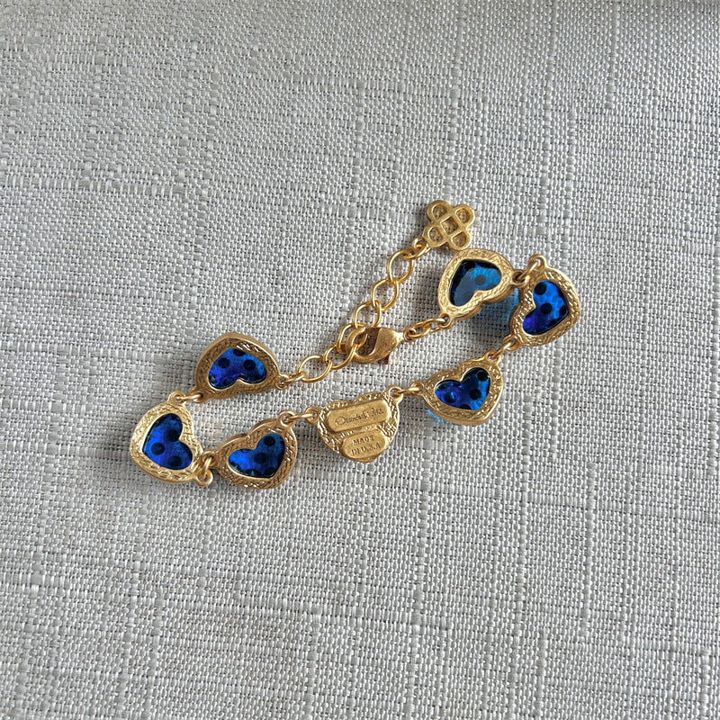 Heart bracelet with blue enamel heart charms and gold-tone chain, small logo tag at center