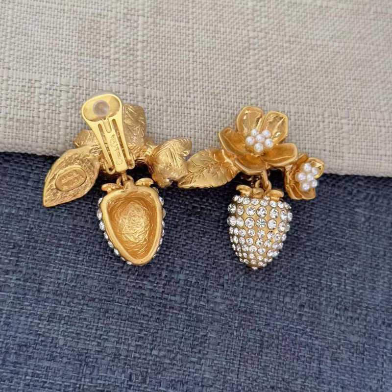Gold-tone clip-on earrings with pearl flower details and rhinestone strawberry charm cluster