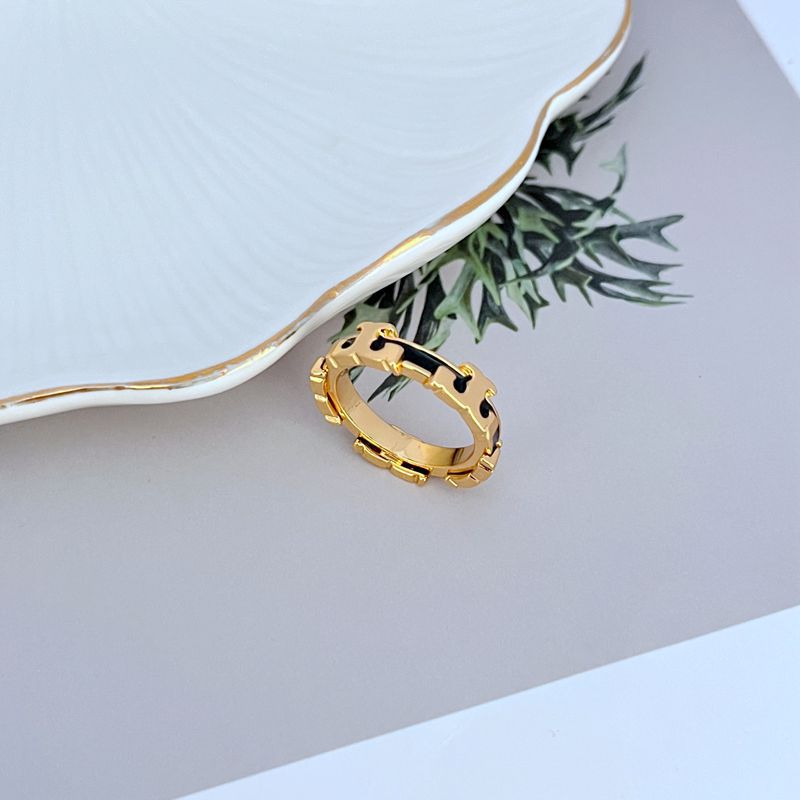 Gold enamel geometric circle metal ring with black enamel accents on the open gold band