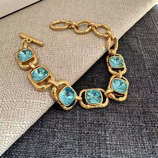 Gold-tone crystal toggle bracelet with turquoise square stones and toggle bar clasp